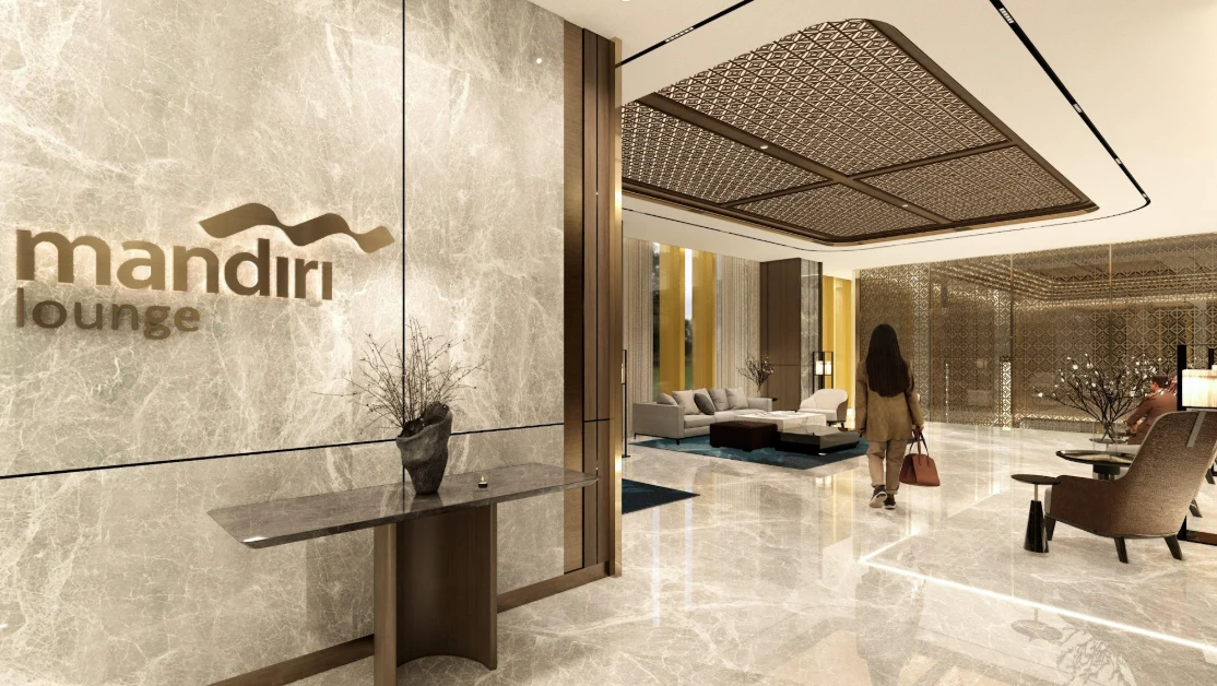 Entrance Mandiri Lounge — dinding marmer abu-abu dengan logo emas brass dan plafon geometrik Nusantara